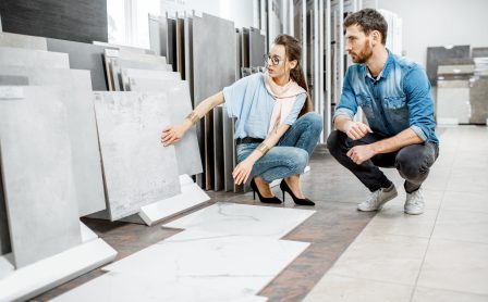 Beautiful young couple choosing big granite tiles for their house repairment in the building shop